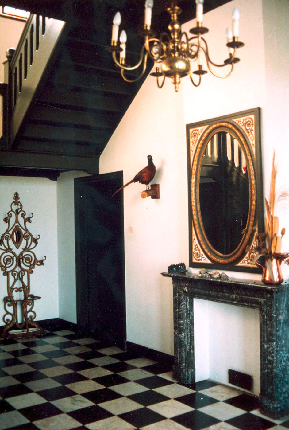 Interieur van de borg met rechts een schouwombouw met daarboven een mooi versierde spiegel en een kroonluchter. Links de trap omhoog.