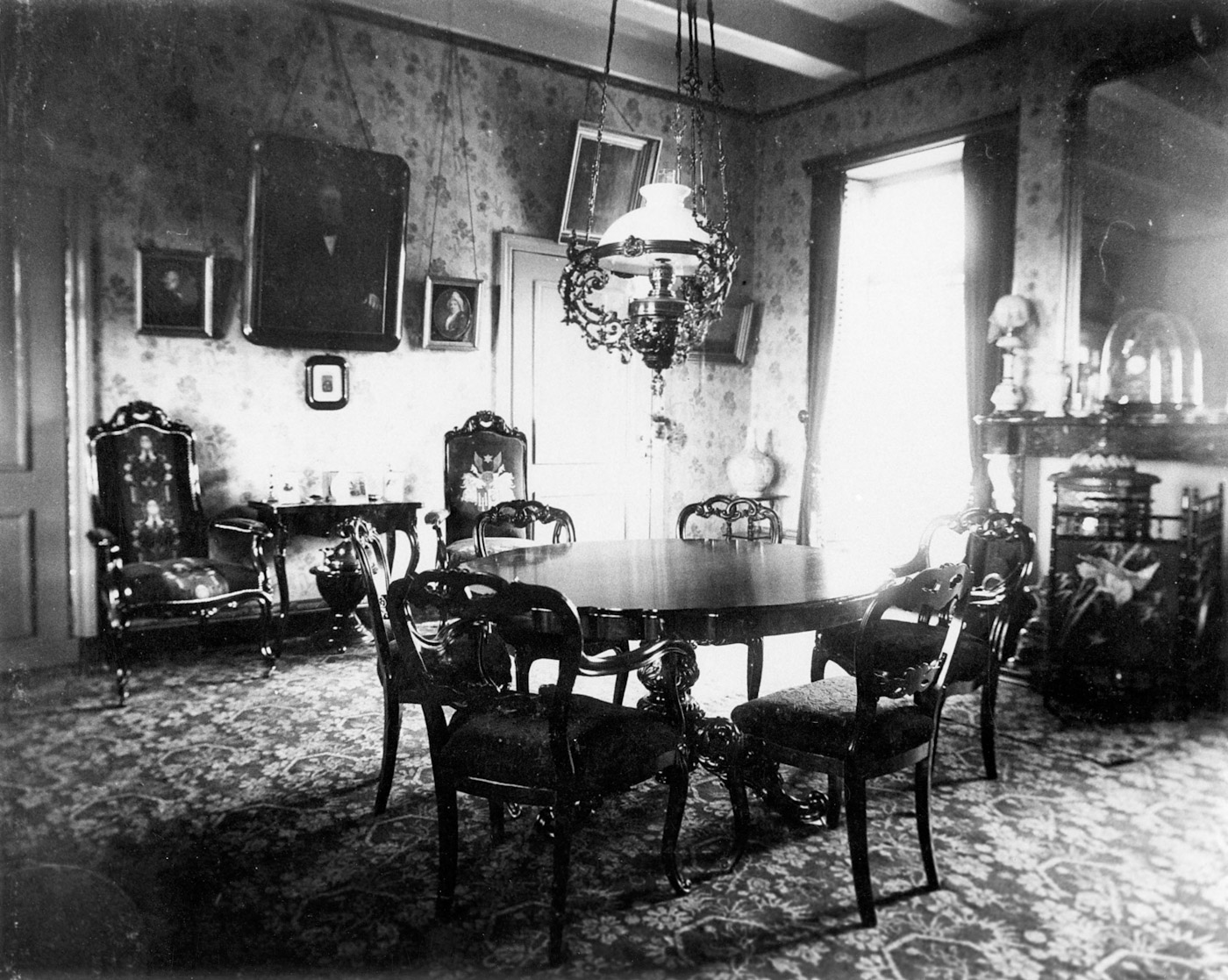 Het klassieke interieur van de borg met op de voorgrond een tafel met klassieke stoelen. Op de achtergrond onder andere een klassieke schouw en nog twee stoelen met een wandtafel. Ook hangen er verschillende schilderijen aan de muur.