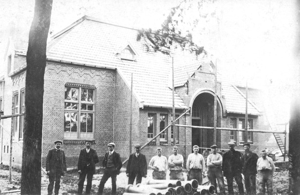 De bouw van de school aan het Roomslaantje, later Middenstraat. Op de voorgrond de mensen van de bouw.