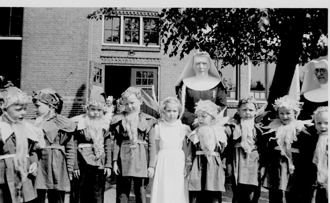 leerlingen met twee nonnen, staande voor de zij-ingang van de school aan het Roomslaantje. In het midden vermoedelijk zuster Marcelien en rechts zuster Lambertine.