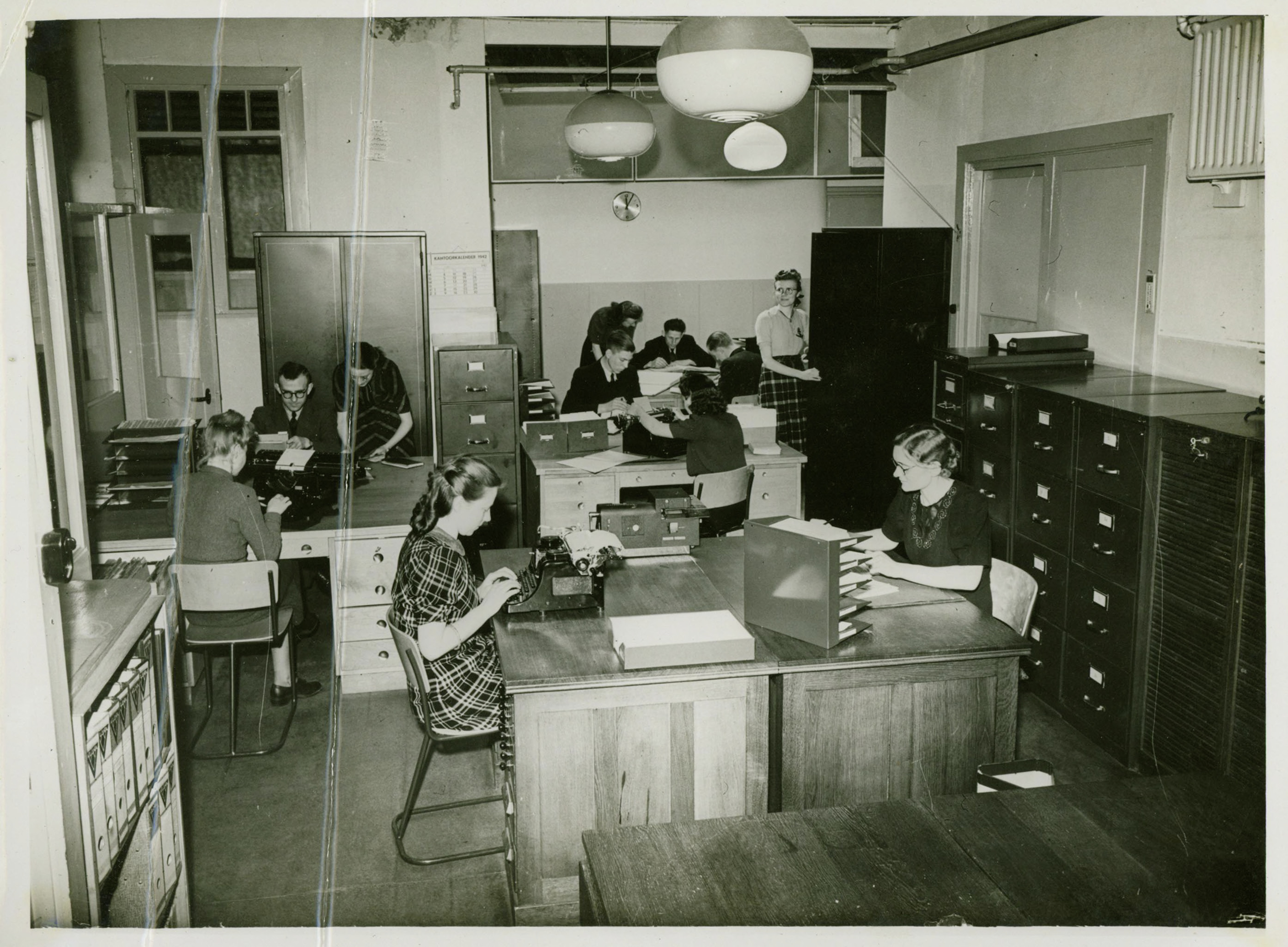 Interieur van de kantoorboekenfabriek Atlanta NV : binderij. Werknemers poseren op hun werkplek.