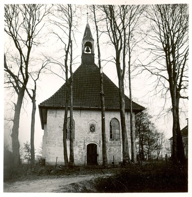 De Nederlands Hervormde Kerk in Kolham met in de top een bel. Op de voorgrond lange dunne bomen.
